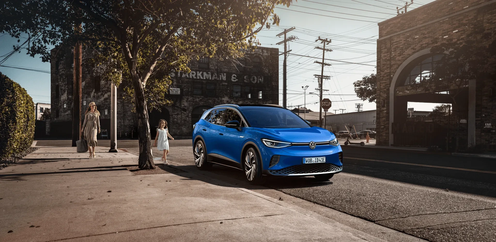 Blauer Volkswagen ID.4 mit einem Mädchen in einer sonnenbeleuchteten Straßenszene — Photo Design von Michel de Vries